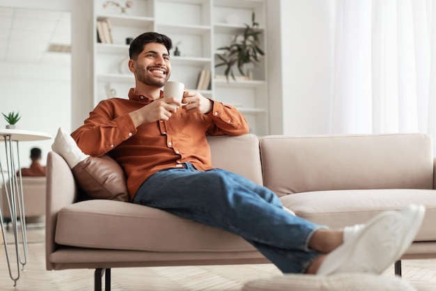 Foto uomo che riposa a casa sul divano a bere caffè