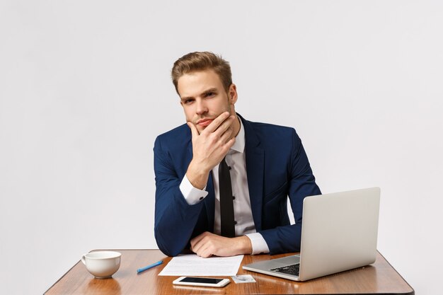 Man having serious conversation, presume something, have deep thought about coworker words. Handsome businessman in office, sitting touching chin as thinking, white background