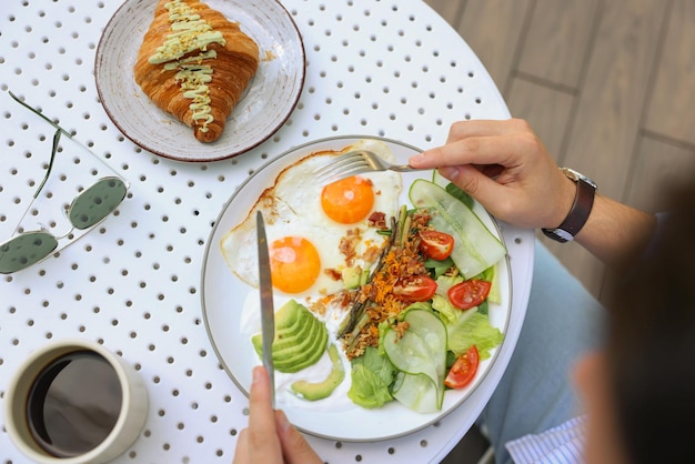 Мужчина ест вкусный завтрак в открытом кафе с верхнего вида