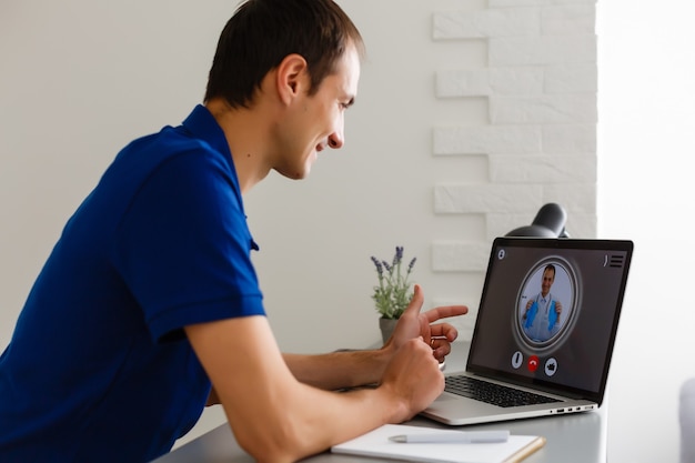 Man having video chat with doctor on laptop at home