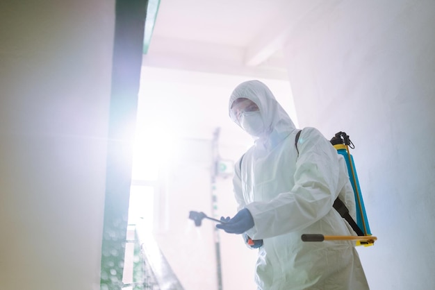 Man in Hazmat suit disinfect the entrance of a residential building