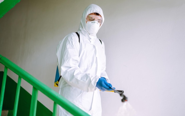 Man in hazmat suit disinfect the entrance of a residential building