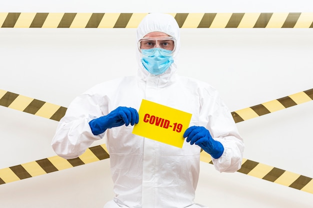 Photo man in hazmat suit with covid-19 sign