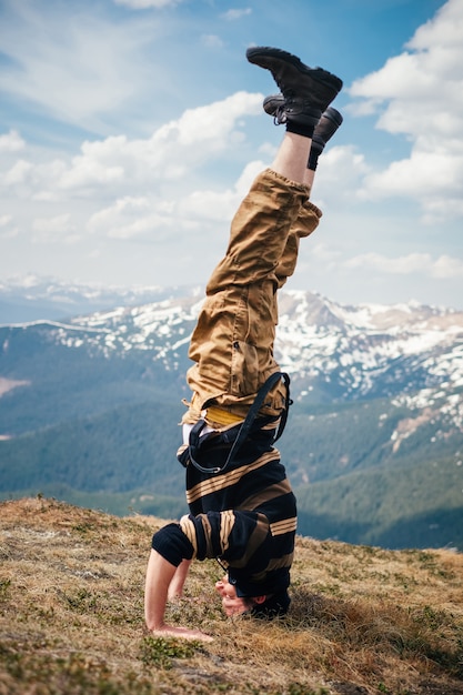 Photo man headstand on the ground in mountains