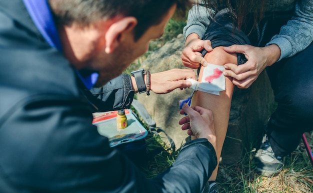 Man healing knee to woman who has been injured trekking