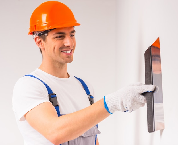 A man in a helmet painter paints a wall and smiles.