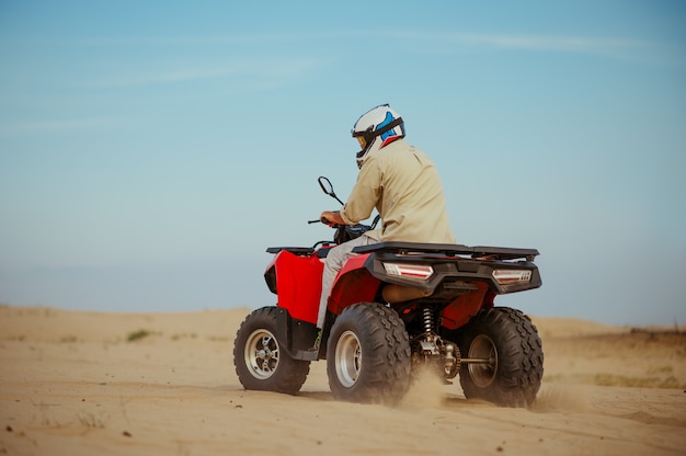 Man in helmet rides on atv in desert, action view