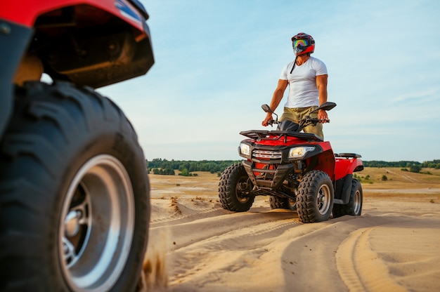 Man in helmet rides on atv in desert sands