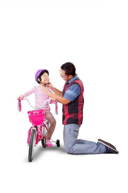 Man helping his daughter to wear helmet on studio