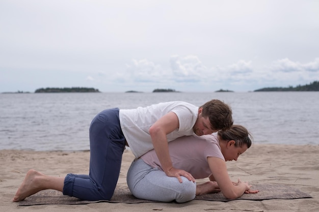 Man helping woman to do a yoga exercise butterfly pose or Baddha Konasana