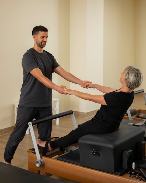 Foto man helpt vrouw in pilatesles.