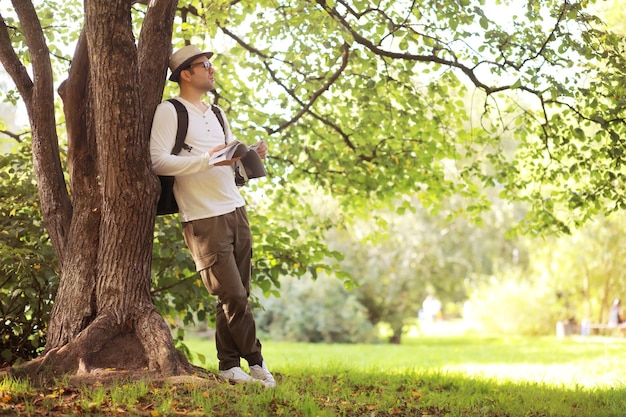 A man hides in the shade of trees on a hot day. Lunch break. Rest in the middle of the working day.