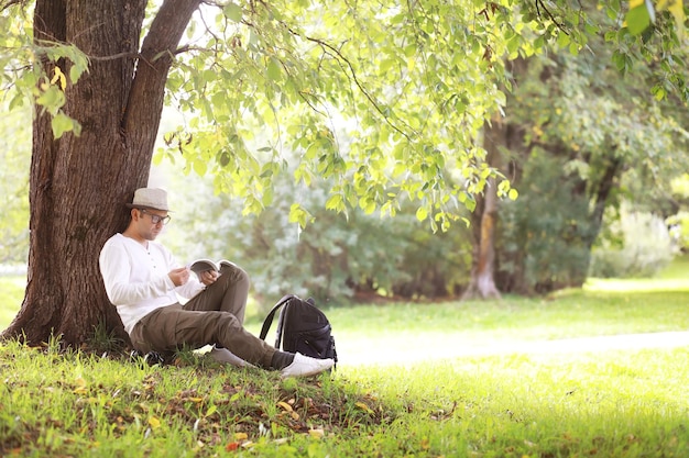 A man hides in the shade of trees on a hot day. Lunch break. Rest in the middle of the working day.