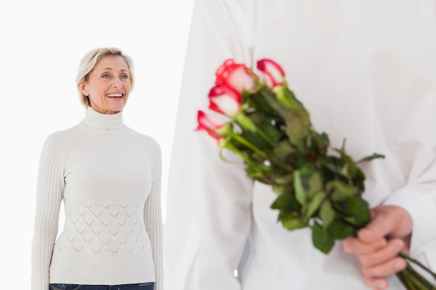 Man hiding bouquet of roses from older woman