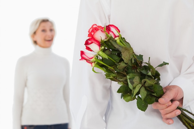 Man hiding bouquet of roses from older woman