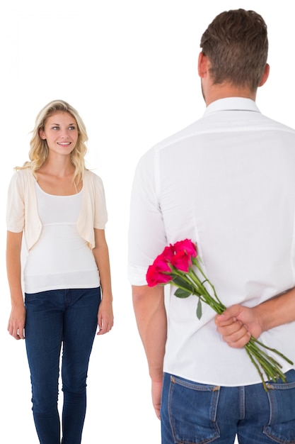 Man hiding bouquet of roses from young woman