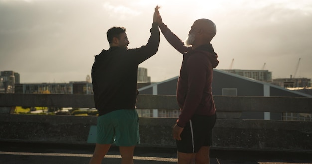 Man high five and fitness in city for workout training or success in outdoor exercise together male person athlete or team touching hands for winning teamwork or sports achievement in urban town