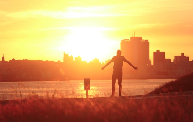 Man hiker silhouette with arms outstretched enjoy mountains