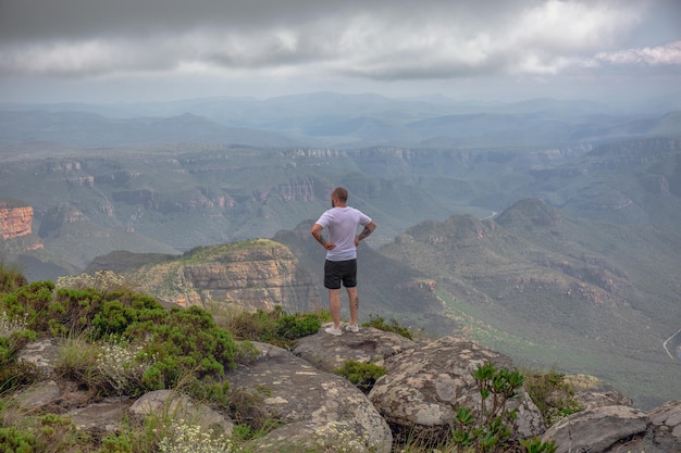 Blyde River Canyon South Africa의 절벽에 있는 돌 위에 서 있는 남자 등산객