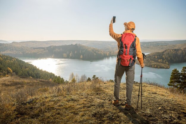 Man hiker taking selfie by smartphone in mountains at sunset Travel and active lifestyle concept Banner with copy space