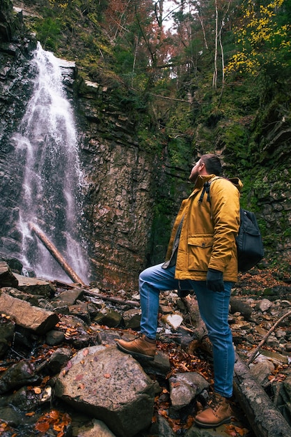 Man hiking concept looking at waterfall in dip forest