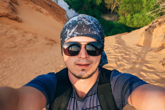 Man Hiking maakt een selfie op het gezicht van de camera in zonnebril en een bandana