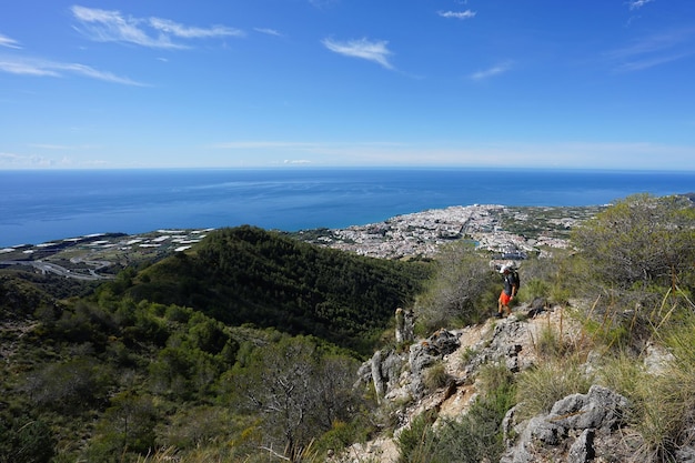 Foto uomo che cammina sulla montagna contro il mare