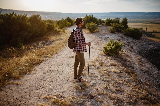 Man hiking in the mountains using pole and looking away