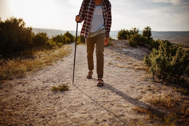 Man hiking in the mountains using pole and looking away