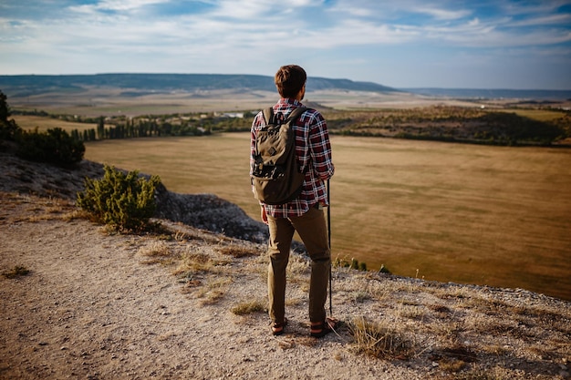 Man hiking in the mountains using pole and looking away