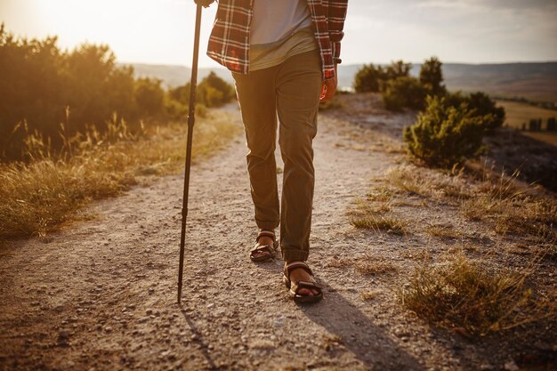 Man hiking in the mountains using pole and looking away