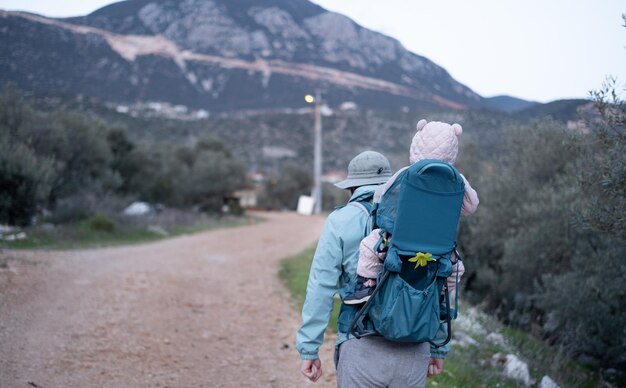 bacpackslingcarrierfamilytravellingtripslifestylefatherchilで赤ちゃんを運ぶ山でハイキングする男