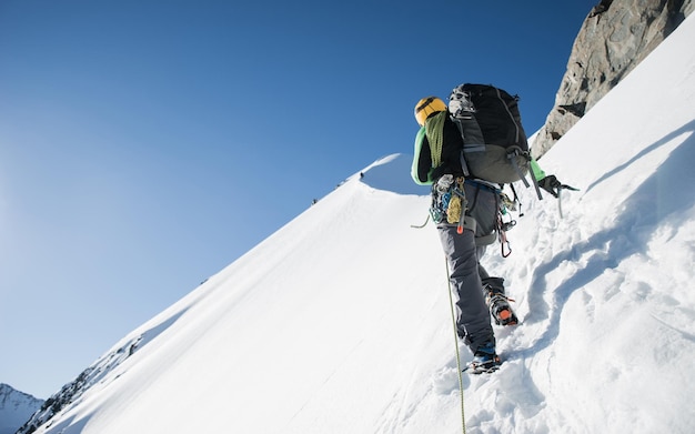晴れた日に雪に覆われた山をハイキングしている男