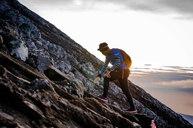 Photo a man hiking up a mountain with a backpack and a backpack