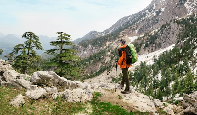 Uomo che fa un'escursione con lo zaino in alta montagna verde in turchia. osservazione del paesaggio durante una breve pausa sulla via licia vicino a tahtalã„â± top.