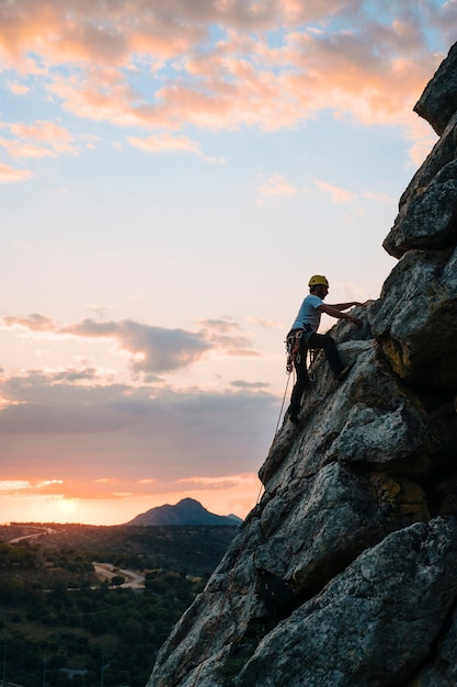 Man in his 30s climbing a mountain at sunset