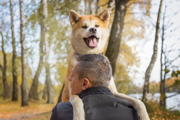 Мужчина и его собака акита-ину в осеннем лесу
