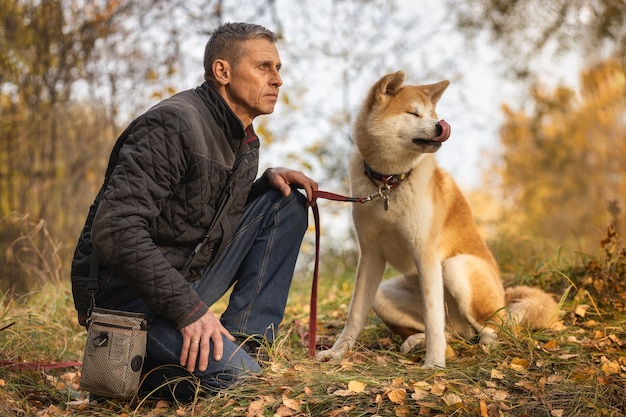 A man and his Akita Inu dog in the autumn forest