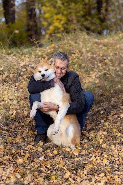 Photo a man and his akita inu dog in the autumn forest