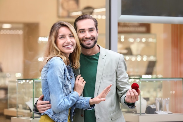 Мужчина и его любимая девушка с кольцом возле ювелирного магазина