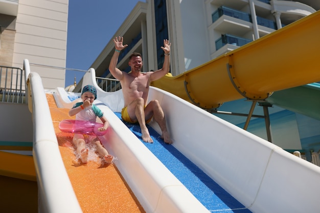 Man and his daughter ride slide in water park