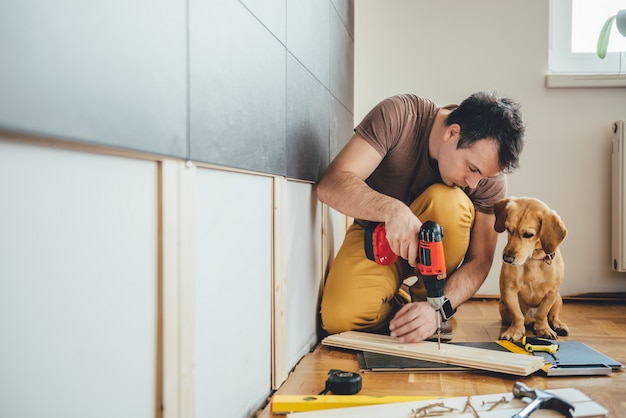 L'uomo e il suo cane facendo lavori di ristrutturazione a casa