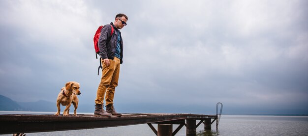 Man and his dog standing on wooden dock 