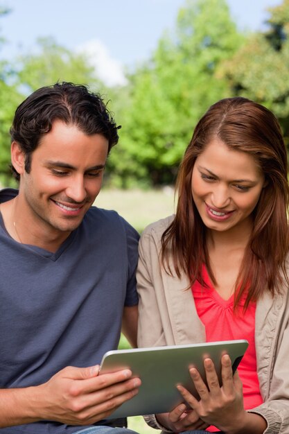 Man and his friend smiling as the watch something on a tablet