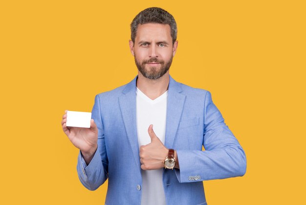 Man hold business credit card isolated on yellow thumb up man with business credit card with copy space man holding business credit card in studio man in jacket hold business credit card