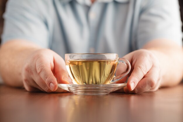 男は手にカップを保持し、お茶を提供