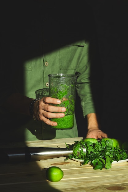 Man hold healthy detox smoothie, cooking with blender with fresh fruits and greens spinach,  lifestyle detox concept. vegan drinks.