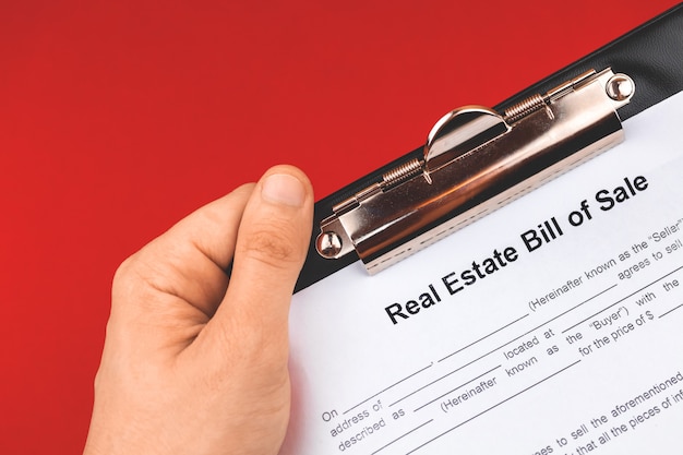 Man hold real estate bill of sale form. mortgage concept. red
background photo