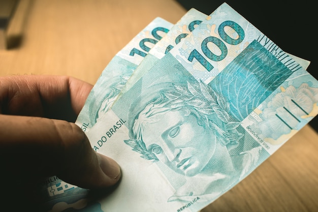 Un uomo con in mano banconote da 100 reais del real brasiliano