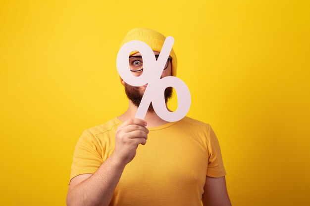 Man holding 3D white percentage sign over yellow background, big sales concept